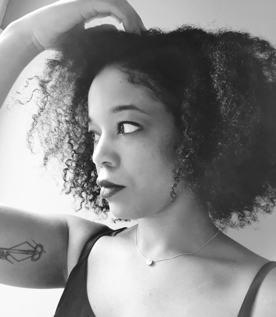 Black and white photo of black woman with natural hair and arm tattoo. Helps readers get to know the writer